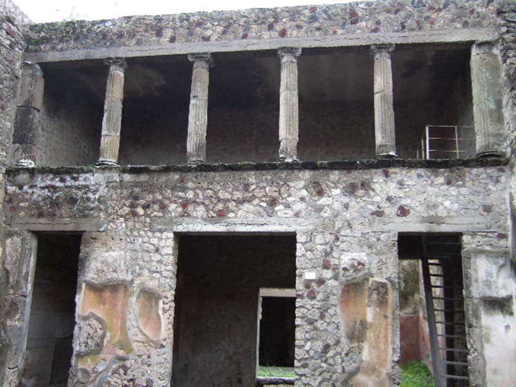 V.2.h Pompeii. December 2005. South side of atrium. Doorways to cubiculum g, tablinum f (in centre), and room e with stairs. According to NdS, the floor of the atrium was Opus signinum, and the walls were covered with a rustic white plaster, except the two walls flanking the doorway to the tablinum, which were decorated with a yellow background and a black dado. On the yellow part was a painted peacock of more or less its natural size, before which, on the wall to the right, was a basket full of grapes, and on that to the left were fruits (pomegranates?) placed on the ground. In both of the walls to the sides of the tablinum, traces of fire could be seen.