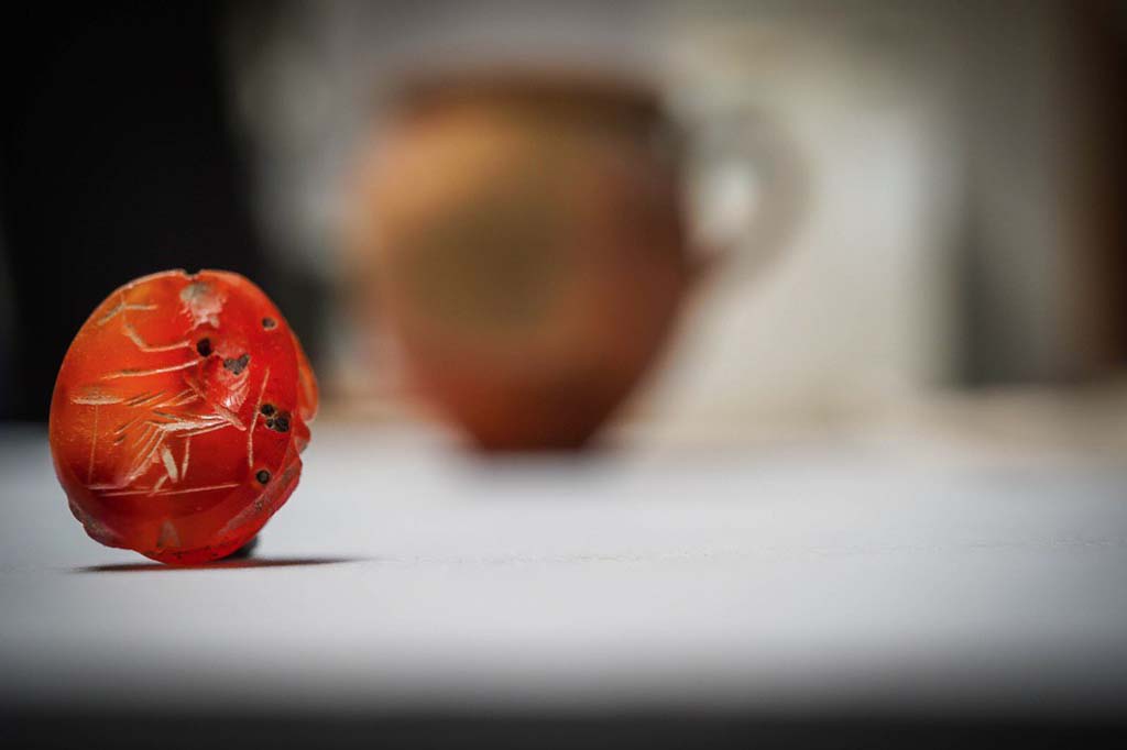 V.3 Pompeii. Casa del Giardino. August 2019. An engraved carnelian.
                                                           
Una corniola incisa.

Photograph © Cesare Abbate/ANSA courtesy Parco Archeologico di Pompei.
