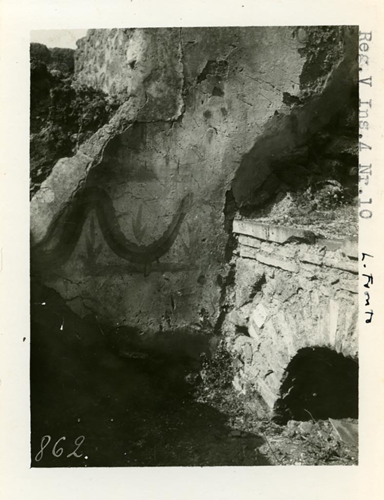 V.4.a Pompeii but shown as V.4.10 on photo. Pre-1937-39.
According to Boyce, on the west wall of the kitchen entered from the north-west corner of the peristyle, was a fragmentary Lararium painting.
One figure of a Lar was preserved, as well as the Genius pouring a libation, a Camillus, and below one red and yellow serpent advancing to the right.
A second and smaller picture had been subsequently painted over the top of that one, but only one Lar remained of that one too.
On the south wall, to the left of the entrance, was painted a ham.
See Boyce G. K., 1937. Corpus of the Lararia of Pompeii. Rome: MAAR 14. (p.42, no.128)
Photo courtesy of American Academy in Rome, Photographic Archive. Warsher collection no. 862.