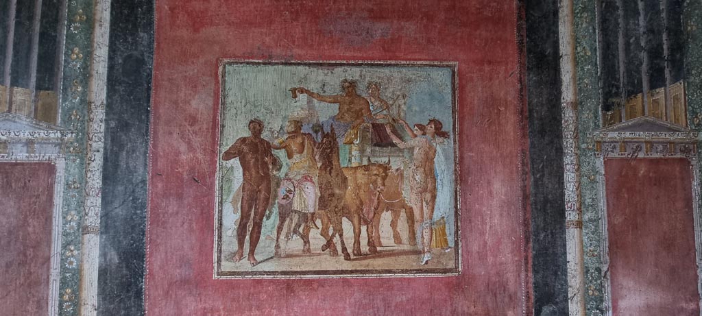 V.4.a Pompeii. January 2023. 
Room ‘h’, central panel on south wall with painting of Bacchus and Ariadne riding on a chariot drawn by two oxen.
Photo courtesy of Miriam Colomer.

