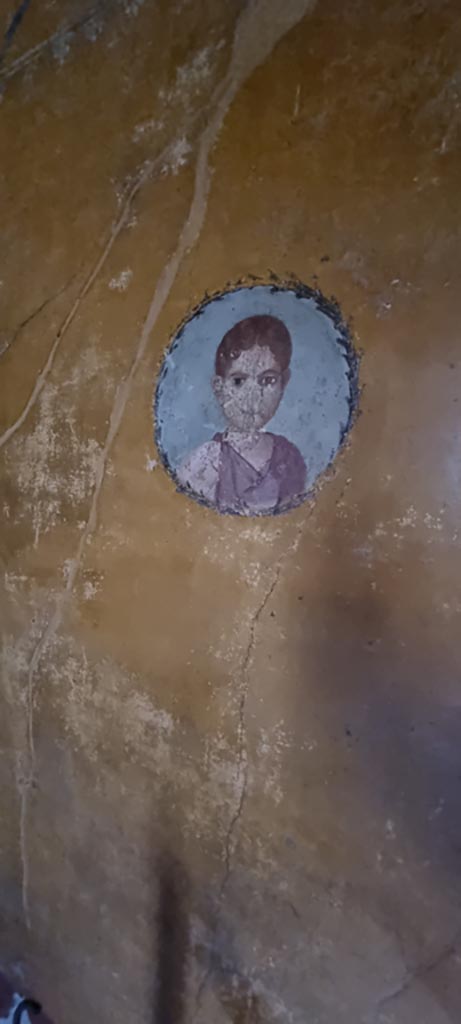 V.4.a Pompeii. January 2023.
Room ‘i’, medallion with painting of girl on west wall of cubiculum on south side of doorway to atrium. 
Photo courtesy of Miriam Colomer.

