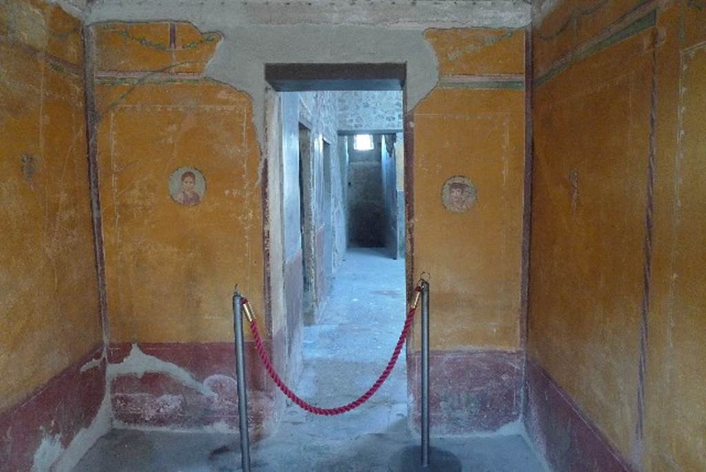 V.4.a Pompeii. July 2010. Room ‘i’, west wall of cubiculum, with doorway to atrium.
On the walls are portrait medallions, one of a young girl and one of a boy with the attributes of Mercury (winged helmet and caduceus).
A large painting is of Pero suckling her father Micone and has a Latin inscription in white letters in the top left corner.
Photo courtesy of Michael Binns.