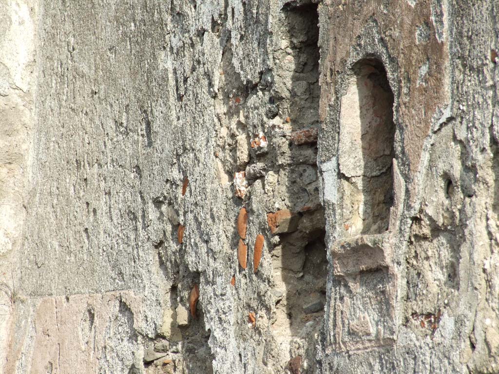 VI.1.1 Pompeii. December 2007. Arched niche on east wall of room 10 (see Mazois plan), photo taken from VI.1.4. 
Originally this niche was at the end of a passage from the triclinium.
The wall around the niche was painted with red stucco. Red, rose-like flowers were painted inside the niche.
See Boyce G. K., 1937. Corpus of the Lararia of Pompeii. Rome: MAAR 14. (p.43, no.132)
See Fröhlich, T., 1991. Lararien und Fassadenbilder in den Vesuvstädten. Mainz: von Zabern. (L55, Picture 37,1)
