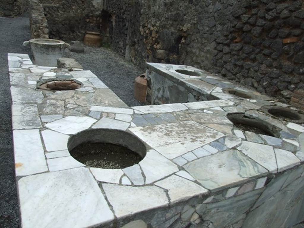 VI.8.8 Pompeii. March 2009. Marble counter, with six urns and hearth.