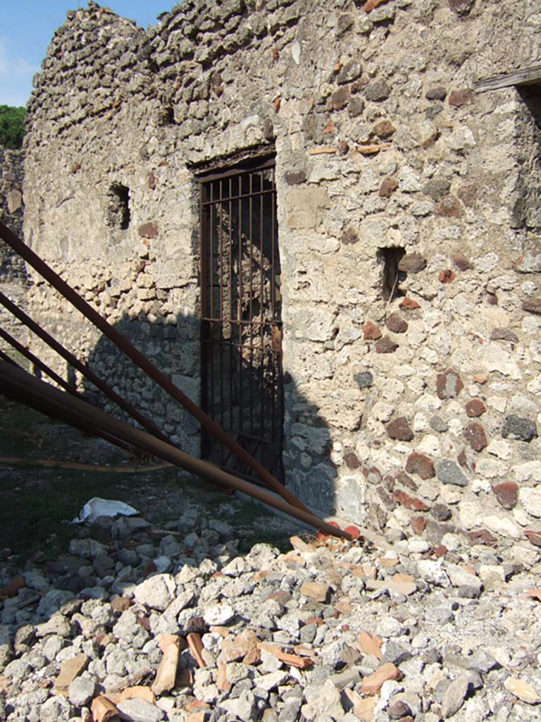 VI.11.8 Pompeii. September 2005. Entrance doorway.
According to Garcia y Garcia, this beautiful house, that had preserved the remains of some of its upper floor which had been restored after excavation, was badly hit in 1943.
The night bombardment of 16th September 1943 destroyed the rooms on the south side of the atrium, and all the remains of the upper floor.
It was then again left derelict and ruined.
The entrance doorway was then bricked in and it was only accessible through two openings made in modern times.
One through the bakery of House of the Labyrinth, the other through part of the falling down western wall, south of the authentic entrance number 8.
See Garcia y Garcia, L., 2006. Danni di guerra a Pompei. Rome: L’Erma di Bretschneider. (p.82)

According to Della Corte, an electoral recommendation was found here at this doorway, reading –
Eutychi    [CIL IV 1369].
He hypothesised that Eutychi may have been the faithful servant/procurator, who stayed too long before fleeing from the eruption. 
A skeleton was found in the lapilli, high up above the peristyle of VI.11.9/10, with a group of precious objects together with a key and seal registered to him and with the letters – Eutychi 
See Della Corte, M., 1965. Case ed Abitanti di Pompei. Napoli: Fausto Fiorentino. (p.44)
According to G. Luongo et al, the skeleton found above the peristyle was a woman.
See Luongo, G. et al. (2003): Journal of Volcanology and Geothermal Research 126, (p.195)
According to Pagano and Prisciandaro, found in March 1835 in the middle of the peristyle but above the original soil level, was a skeleton.
Nearby were two gold circles, perhaps armbands or bracelets, (MN 24992 and 24993); three gold rings and an iron key, together with a bronze seal with an inscription –
Euti
chi     [CIL X 8058,33]
These objects are now in Naples Archaeological Museum, inventory numbers 4755, 25830, 25831, 25832.
See Pagano, M. and Prisciandaro, R., 2006. Studio sulle provenienze degli oggetti rinvenuti negli scavi borbonici del regno di Napoli. Naples: Nicola Longobardi, (p.150) PAH, II, 304-5.
