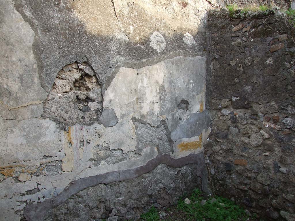 VI.11.19 Pompeii. December 2007. East wall of the room (9) cubiculum, the middle room on south side of the atrium.  
This room was described as having a black zoccolo (the lower part of wall).
The white middle background to the wall had painted square panels of yellow and red, the upper wall was white with red panels.
