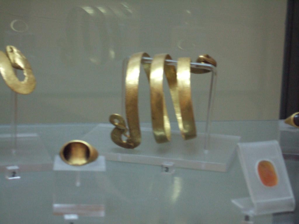 VI.12.2 Pompeii. Found 4th March 1831. Gold bracelet with body of a serpent (at back). Inventory number 24825.
Gold ring (on left). Inventory number 25107.
Carving on cornelian of bust of a youth, possible Alexander the Great (on right). Inventory number 26766.
Now in Naples Archaeological Museum. 
