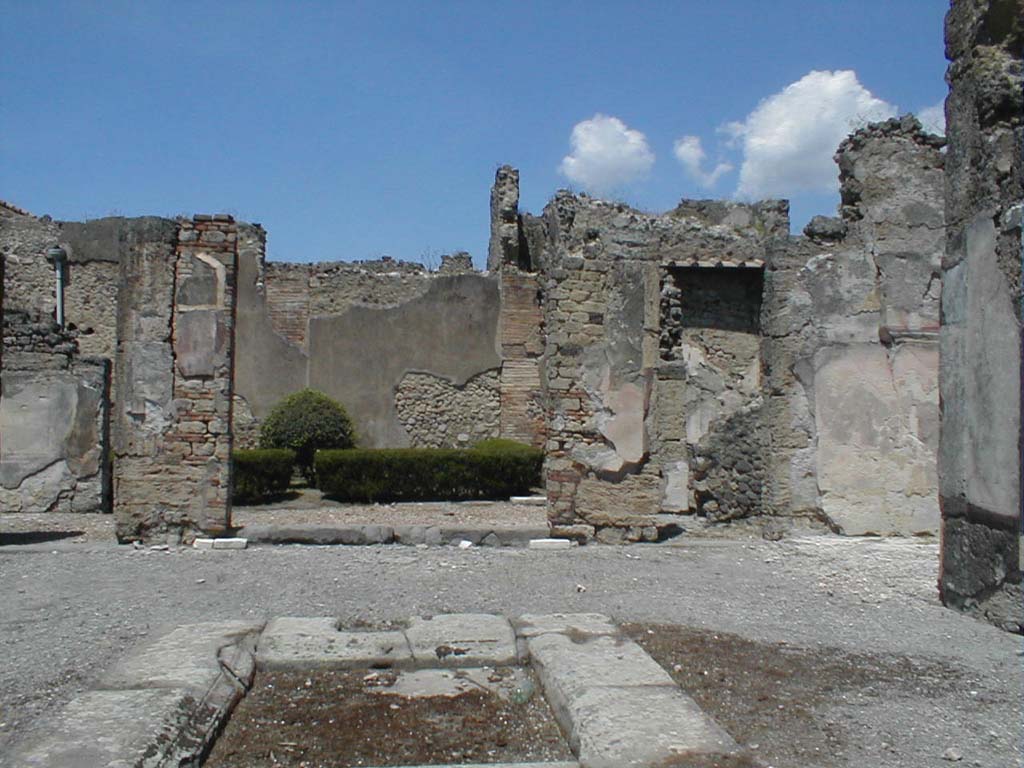 VI.14.12 Pompeii. May 2005. North-east side of atrium, with doorway to garden in the centre.
In the north-east corner is the doorway leading to the winter triclinium, and steps to upper floor. On the right, the east ala can be seen.