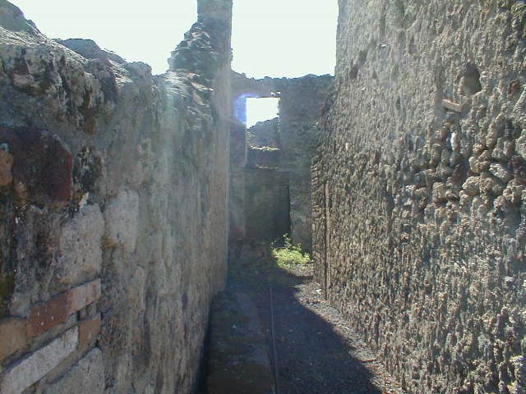 VI.14.27 Pompeii. September 2004. Looking west along entrance corridor towards a doorway leading to the small room, perhaps the kitchen, in the south-west corner of the atrium. The room above would have been accessible by stairs leaning against the south wall of the atrium.

According to Wallace-Hadrill, this corridor led to the atrium and five rooms, wine containers were found at the rear. It was thought to be an establishment of a vinarius (wine-dealer). No decoration was found in any room.
See Wallace-Hadrill, A. (1994): Houses and Society in Pompeii and Herculaneum. Princeton Univ. Pr., (p.213) 

According to Della Corte, this house was named following the discovery of a seal/signet belonging to  M. Memmius Auctus   [CIL X 8058, 50]
See Della Corte, M., 1965.  Case ed Abitanti di Pompei. Napoli: Fausto Fiorentino. (p.96, S.59 with Note 1)

According to Jashemski, in a small courtyard at the rear of the house, excavated in 1875, four small marble busts of philosophers were found. They are now in Naples Archaeological Museum with inventory numbers 110872-110875. They had been cut down, as if to be placed back to back as double-herms, but no two herms, according to Dwyer, seemed to fit together. Perhaps they were being stored here. There were also four terracotta dolias embedded in the soil.
See Jashemski, W. F., 1993. The Gardens of Pompeii, Volume II: Appendices. New York: Caratzas. (p.150)
See Dwyer: Pomp Sculpture, p.128. 

According to Garcia y Garcia, several dividing and perimeter walls were destroyed due to the 1943 bombing. Also the impluvium and stairs to the south of the atrium, and the collapse of the omaba in the west wall of the large room to the north of the atrium, that now appears open never having been built again.
See Garcia y Garcia, L., 2006. Danni di guerra a Pompei. Rome: LErma di Bretschneider. (p.91)
