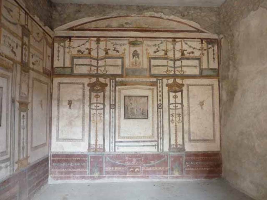 VI.15.8 Pompeii. May 2010. Looking towards east wall of oecus in the south-east corner of portico.
According to Sogliano in NdS, this room was either a triclinium or an oecus.
It had walls painted with decorations partitioned with the usual architectural motifs, on a white background.
The dado was purple.
He said the decoration wanted to be rich and vibrant, but in reality it was bungled, heavy and vulgar.
He thought it made a sad impression as if one was in a catacomb.
Originally it would have contained three central paintings, but only two remained, as the third fell together with the south wall.
On the north wall was Perseus and Andromeda.
On the east wall, Sogliano thought the painting showed Helen and Paris in Sparta.
See Notizie degli Scavi di Antichità, January 1897, (p.36-7)