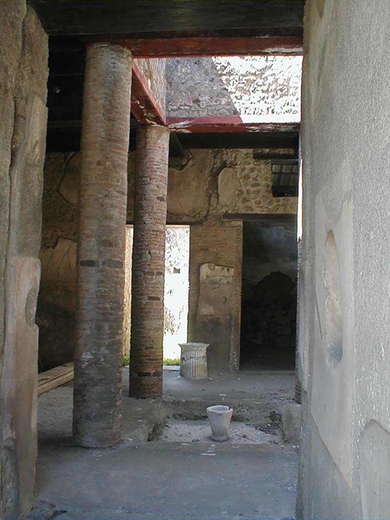 VI.15.9 Pompeii. September 2004. Entrance corridor, looking west to atrium.
According to Richardson, this tiny atrium house had a very efficient design.
The atrium is entered by short fauces flanked by cubicula with windows to the street.
The atrium is almost square, Tetrastyle with columns of naked brick that supported a second floor.
The second floor was a gallery lit by large rectangular windows into the compluvium well.
It was accessible by a small staircase against the north wall of the atrium.
Although it must have made the atrium rather dark, it made living space available over the atrium, as well as over the cubicula at the front of the house.
On the far side of the atrium, opened an ample triclinium and the service area.
This service area in the south-west corner of the house was lit by a second light-well and had a second storey of its own, possibly just a loft for storage.
See Notizie degli Scavi di Antichitŕ, 1897, 38-39, 62-64.
See Richardson, L., 1988. Pompeii: An Architectural History. Baltimore: John Hopkins University Press. (p.345-6)
(Note – the staircase is actually against the south wall of the atrium)