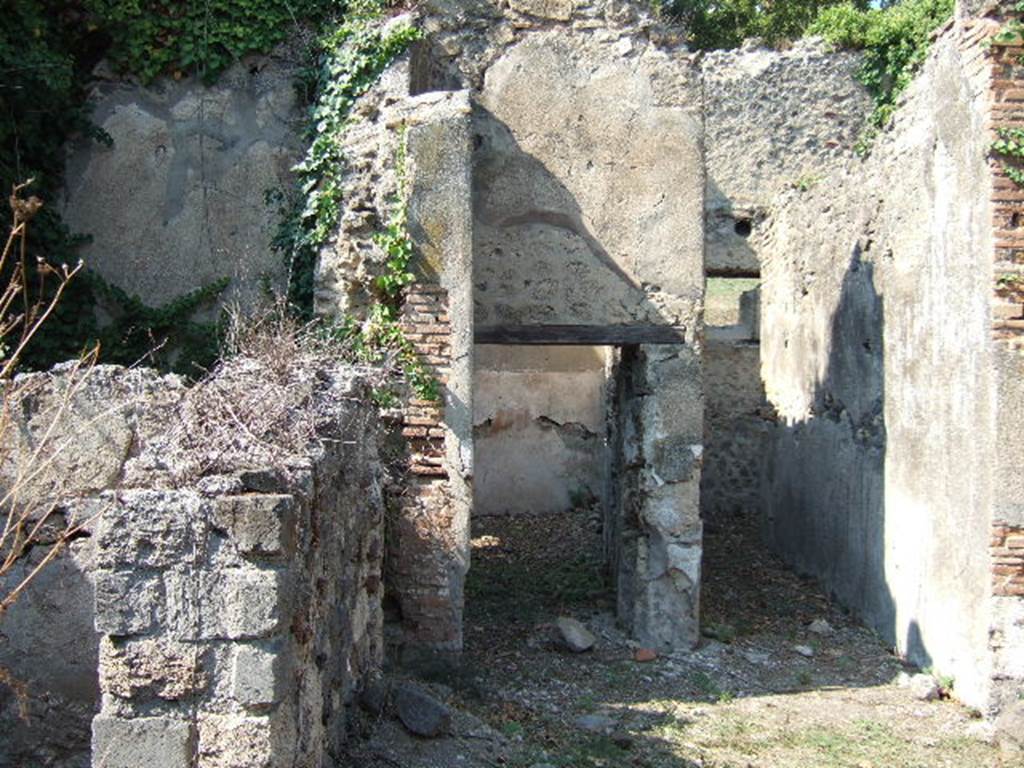 VI.15.20 Pompeii. September 2005. Looking north from atrium, towards doorways to triclinium, centre, and corridor leading to kitchen and latrine, on the right. According to NdS, the corridor had walls faced with white and coarse plaster. The doorjambs of the doorway to the triclinium had portions of red plaster, covered in the last years by other rustic facing of lime. The walls were faced with brick plaster (laterizio), in the west wall were two small windows overlooking the vicolo. In the east wall was a rectangular recess, faced with red plaster. In the excavated earth, a piece of red plaster was retrieved with the figure of a flying psyche (0.16m), and a graffito: PLATOR.
On the pilaster dividing between the triclinium and corridor, Sogliano could read a graffito on the black dado:
IIROS
IIVRVS
See Notizie degli Scavi, June 1897, (p.274-5)