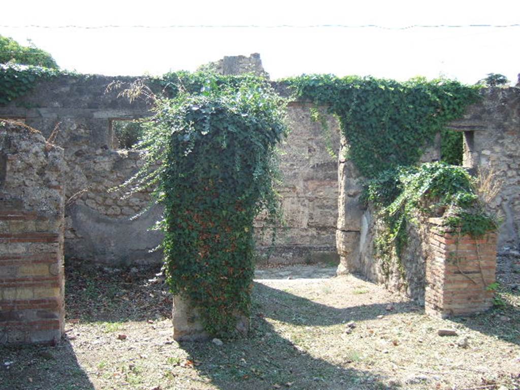 VI.15.20 Pompeii. September 2005. Looking west across atrium towards doorways to cubiculum, on left, and entrance doorway, in centre. According to NdS, the cubiculum had a mezzanine above it, and had walls of coarse white plaster. In the north wall it had a rectangular recess. In the east wall was another rectangular recess, in which the holes for shelving supports could be seen. In the west wall was a window overlooking the vicolo.
In 1897 when excavated, in the proximity of the left doorjamb of the cubiculum, or north of it in the atrium, was another terracotta puteal. In the west wall of the atrium was a brick niche, and in the south wall were the holes for the joists that probably supported a mezzanine. The holes were at a height of 3m. from the ground level. See Notizie degli Scavi, June 1897, (p.274)