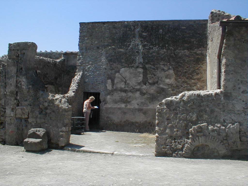 VI.16.6 Pompeii. May 2005. Looking west towards entrance doorway to wide room of fullonica.
According to Sogliano, the entrance doorway threshold was made of lava.
In the left half could be seen a longitudinal track for fixing a board for closure.
In the other half (the right side) the track was missing, and the remains of a hinge proved that there had been a movable shutter of a door there.

In the south-west corner of the west wall is a doorway into what now appears to be a corridor leading to VI.16.7.
According to Sogliano, this actually led into a narrow room which was under the stairs from the peristyle of VI.16.7.
See Notizie degli Scavi di Antichità, 1906, p. 350.
