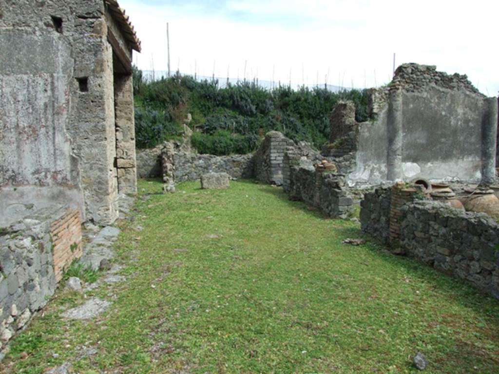 VI.16.27 Pompeii. March 2009. Looking east across north portico.
According to Jashemski, the peristyle garden had a wide portico on the north. The portico was supported by three columns and one engaged column, covered with rough plaster, red at the bottom. They were connected by a low masonry wall with an entrance into the garden between the first and second columns, from the east. Numerous dolia and large jars were found embedded in the soil in the north-east corner of the garden. See Jashemski, W. F., 1993. The Gardens of Pompeii, Volume II: Appendices. New York: Caratzas. (p.164)