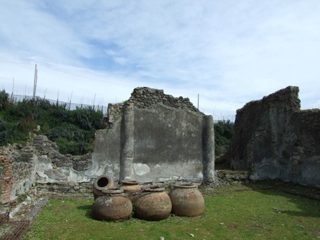 VI.16.27 Pompeii. March 2009. Looking east across peristyle garden M. According to NdS, on the left, would have been the four columns of the north portico, joined by a low brick wall. On the other three sides of the peristyle garden, there was no portico, but semi-columns protruded from the walls. These walls were covered at the top with rough plaster, but had a dado with a black background at their base. This dado was divided into many rectangular panels separated by half-columns and containing paintings of plants, with birds sitting on them, or flying around them. Sometimes the paintings became more interesting, such as in the first panel on the left side of the east wall. This showed two water-birds, one of whom was struggling with a small serpent. In the two central panels of the south wall, there was a peacock in each pecking over a twig with fruit, facing towards each other. In the first panel to the left of the west wall were two water-birds again, one of which in the attitude of fighting with a small serpent. See Notizie degli Scavi, 1908, (p.189-90)