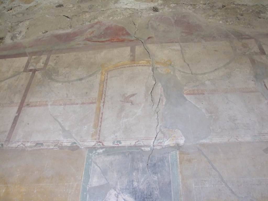 VI.16.27 Pompeii. March 2009. Room G, upper north wall of triclinium. According to NdS, the frieze had a white background and the remains of simple architecture, arabesques and garlands festooned with hanging objects and flying animals. Above the frieze of the north wall, on a red background, two winged creatures faced each other.