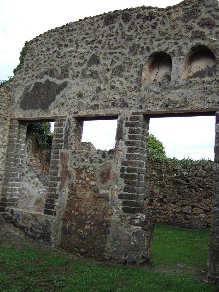VI.16.32 Pompeii. December 2005. 
Room B, east wall of atrium with doorway to room F, garden area with niches above.
According to NdS, in the north-east corner of the atrium was a low masonry wall, on which there was a second smaller one.  
Sogliano seemed to think he could see the void in which the end of a wooden ladder would have been fixed.
The wooden ladder would have leaned against the north wall and given access to an upper floor.
See Notizie degli Scavi di Antichità, 1908, (p.287)
To the left and straight ahead in the east wall were two large windows that gave onto garden F, between them was a doorway to the garden.
Later however, the window on the left and the doorway were bricked up, and the window on the right was changed into the doorway.
The garden F was open and uncovered. 
