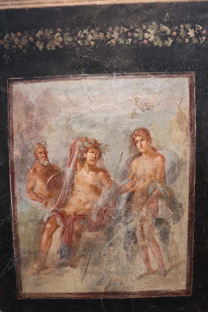 VI.17.42 Pompeii. February 2021.
Fresco showing Dionysus and Ariadne in Naxos, found on the triclinium north wall, on display in Antiquarium at VIII.1.4.
Photo courtesy of Fabien Bièvre-Perrin (CC BY-NC-SA).
Kuivalainen describes –
“A composition of three figures on the shore of a rocky landscape. ……………..”
Kuivalainen comments –
“Instead of portraying Bacchus just discovering Ariadne, the situation here has already developed. He is drunk and making a pass at her. She is standing wide awake, looks a little surprised by the encounter with a tipsy looking stranger, and makes efforts to protect her modesty. The horizontal line is very high.”
See Kuivalainen, I., 2021. The Portrayal of Pompeian Bacchus. Commentationes Humanarum Litterarum 140. Helsinki: Finnish Society of Sciences and Letters, (p.156, E20).