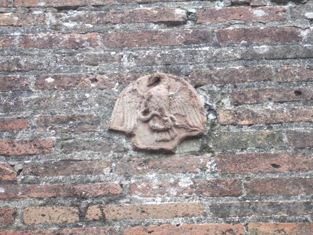 VII.4.56 Pompeii. December 2005. Terracotta plaque with eagle, on wall on east side of entrance. In May 1831, found painted in red and under the plaque of the eagle with a serpent in his claws, was the graffito 
Popidium  Secundum aed(ilem)    [CIL IV 285]
See Pagano, M. and Prisciandaro, R., 2006. Studio sulle provenienze degli oggetti rinvenuti negli scavi borbonici del regno di Napoli. Naples, Nicola Longobardi. 
(p. 145)

