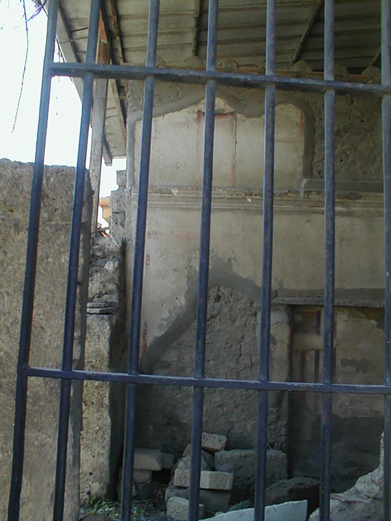 VII.4.62 from VII.4.63, Pompeii. May 2005.
Looking south into cubiculum towards the remains of the upper south wall, across a site of a staircase to upper floor, through window in shop at VII.4.63.