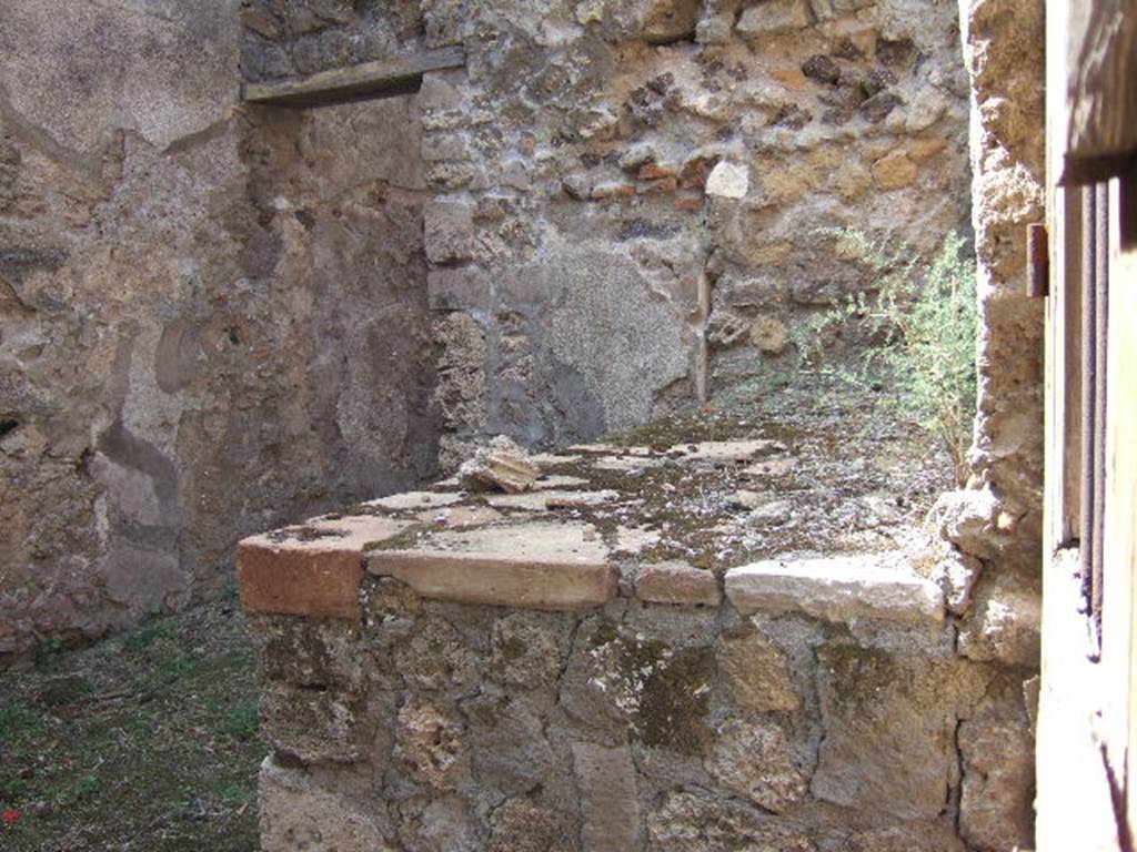 VII.7.14 Pompeii. September 2005. 
Looking west from entrance doorway, along north wall and hearth or bench in kitchen area (s).
