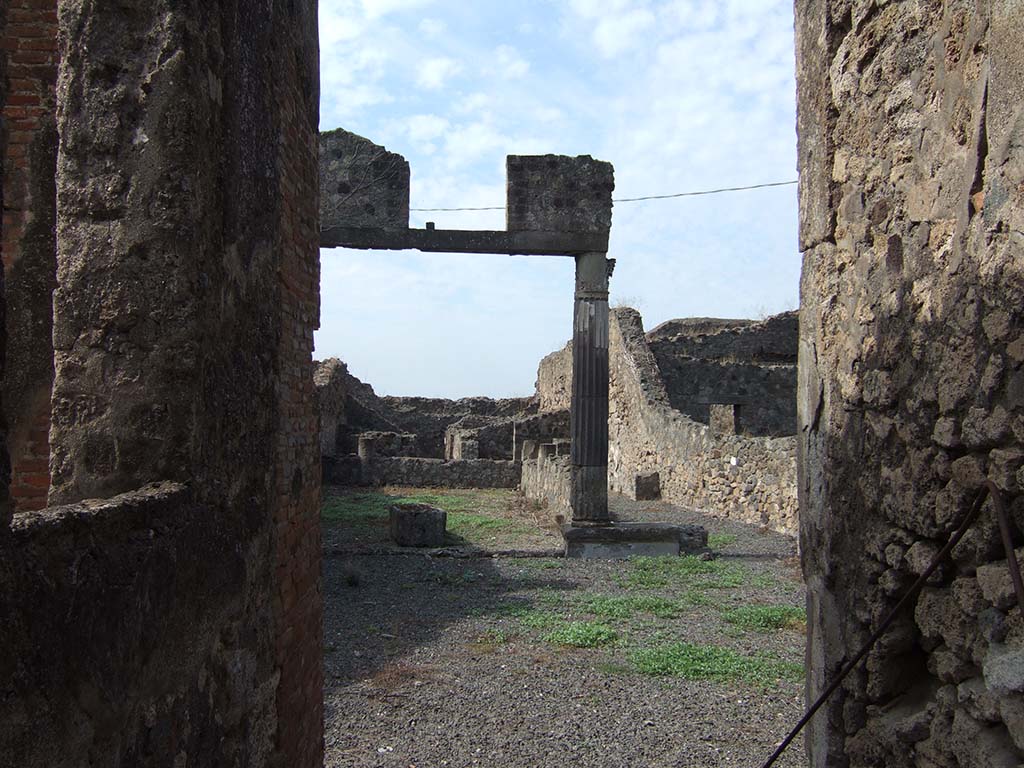 VII.7.23 Pompeii. September 2005. Looking west from entrance across atrium towards entrance to garden area.
According to Jashemski, the peristyle garden at the rear of the atrium was enclosed on the north and west by a portico.
It was supported by five masonry columns, connected by a low masonry wall in which was a terracotta puteal that gave access to the cistern below.
There was a gutter along the north and west edges of the garden.
On the west wall of the portico was a lararium painting, and on the floor in front of the painting was a small masonry altar.
Along the south wall of the garden was a garden bench.
See Jashemski, W. F., 1993. The Gardens of Pompeii, Volume II: Appendices. New York: Caratzas. (p.188)
According to Boyce, on the west wall of the peristyle was a lararium painting of a single large serpent coiling from the right towards a yellow altar.
The altar was furnished with offerings and stood on a base in the midst of plants.
On the floor of the portico, in front, stood a small masonry altar coated with stucco, and having a concave upper surface.
See Boyce G. K., 1937. Corpus of the Lararia of Pompeii. Rome: MAAR 14. (p.68, no.301) 
