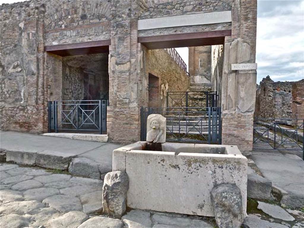 VII.9.68/67 Pompeii. September 2011. Looking north to entrance doorway on left side of fountain. Photo courtesy of Michael Binns. According to Cooke Cockburn and Donaldson, there is a flight of stairs leading into the street by a doorway. At the bottom of the stairs is a small chamber, having an opening into the street, and one on the landing at the foot of the staircase. The walls of this chamber are embellished with various paintings on a black background, among which is a remarkable landscape, having in the distance lofty mountains, a river winding through verdant meadows, with herds and shepherds and views of villas, and in the foreground a statue, before which is a group offering sacrifices. There is a fountain in the street, immediately opposite the door of the staircase. The outer elevation of the walls towards the two streets is decorated in stucco with pilasters, cornices and pediments, lightly relieved, and not inelegant in detai, (see VII.9.67).
See Cooke Cockburn Donaldson, Pompeii, pt. 1, 1827, (p.53)