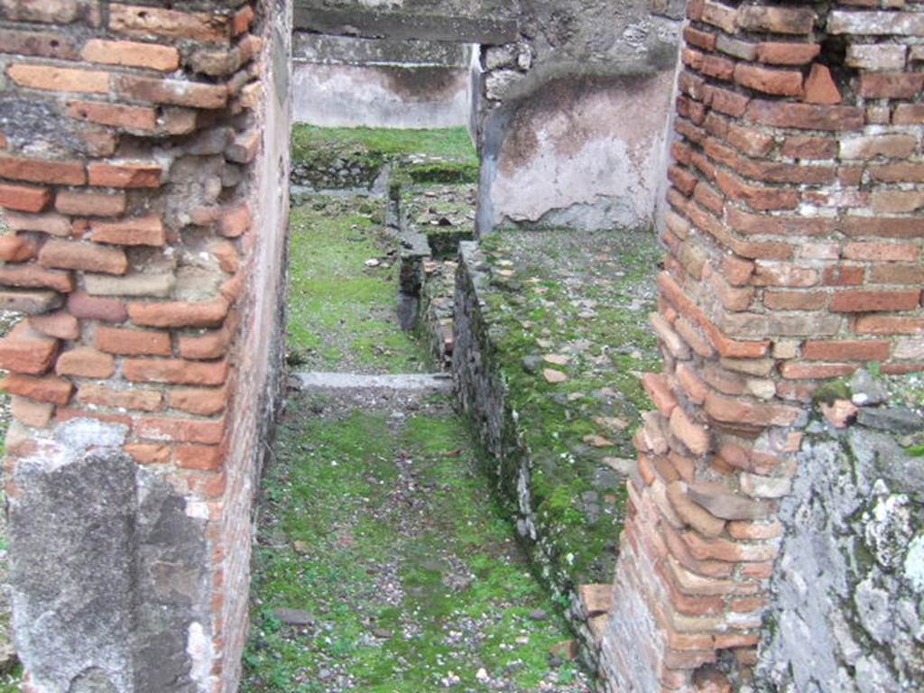 VII.10.5 Pompeii. December 2005. Looking east in rooms leading towards rear entrance doorway at VII.10.13.  According to Amoroso, at the rear of the house, kettles and tubs were installed in a masonry bench. This would seem to indicate that the use of the area was changed perhaps into an “officina lanifricaria”.


