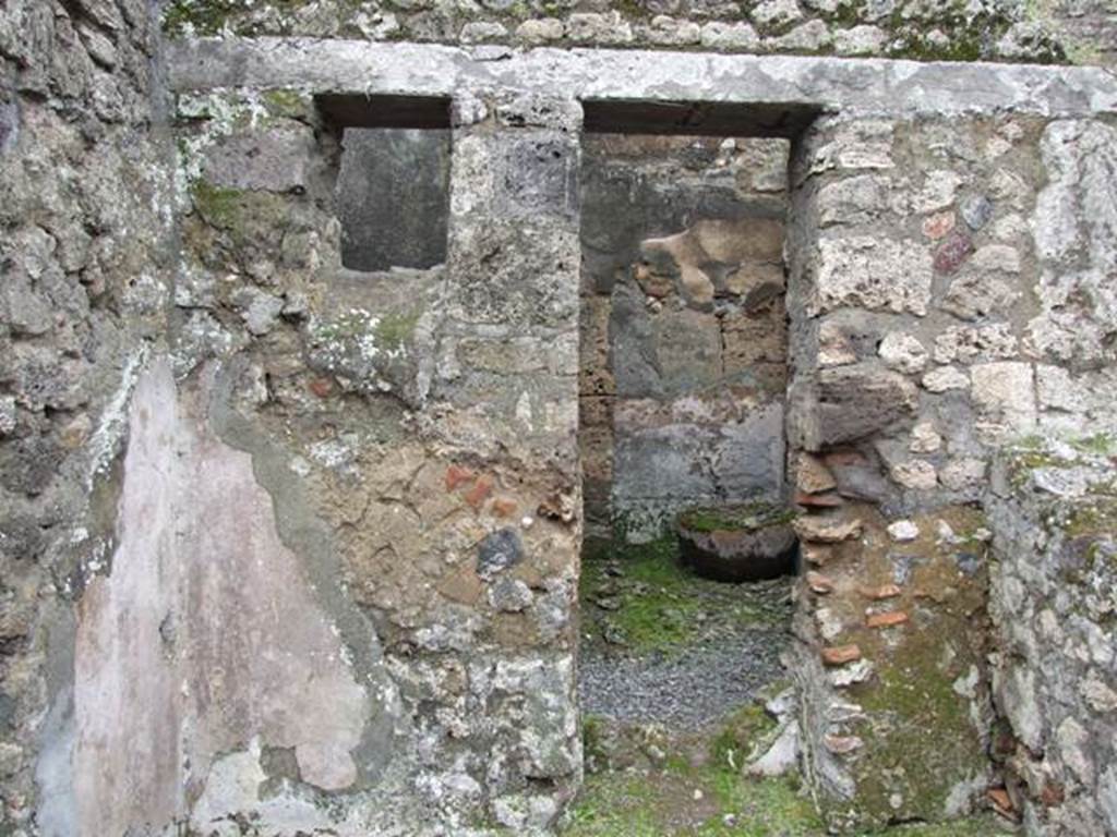 VII.10.12 Pompeii.  March 2009. Looking west at wall with a door with plaster in the lower area.