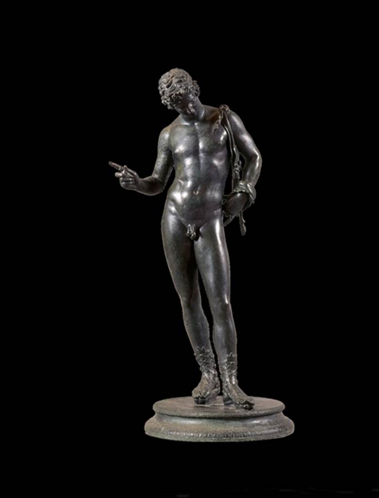 VII.12.17.21 Pompeii. June 1862. Bronze statue found in the small room near the entrance at VII.12.17.
Fiorelli identified it on excavation as possibly a statue of Narcissus.
See Pappalardo, U., 2001. La Descrizione di Pompei per Giuseppe Fiorelli (1875). Napoli: Massa Editore. (p.112).
Mau identified it as a statue of Dionysus, and it is now displayed as this.
See Mau, A., 1907, translated by Kelsey F. W. Pompeii: Its Life and Art. New York: Macmillan. (p.452).
Now in Naples Archaeological Museum. Inventory number 5003.
According to Kuivalainen 
The condition of the statuette is good but the original base has been replaced and the panther is lost.
Kuivalainen comments 
The males apparel and the position of the right-hand fingers identifies the bronze as Bacchus dangling a bunch of grapes above a panther.
The iconographic formula is also known from wall paintings in Pompeii.
See Kuivalainen, I., 2021. The Portrayal of Pompeian Bacchus. Commentationes Humanarum Litterarum 140. Helsinki: Finnish Society of Sciences and Letters, (H14, p.219).
