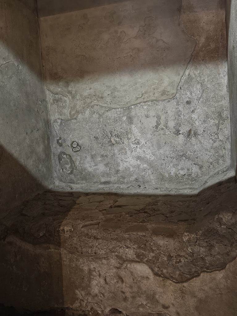 VII.12.18 Pompeii. November 2024. 
Detail of plaster on wall, and stone bed. Photo courtesy of Annette Haug.

