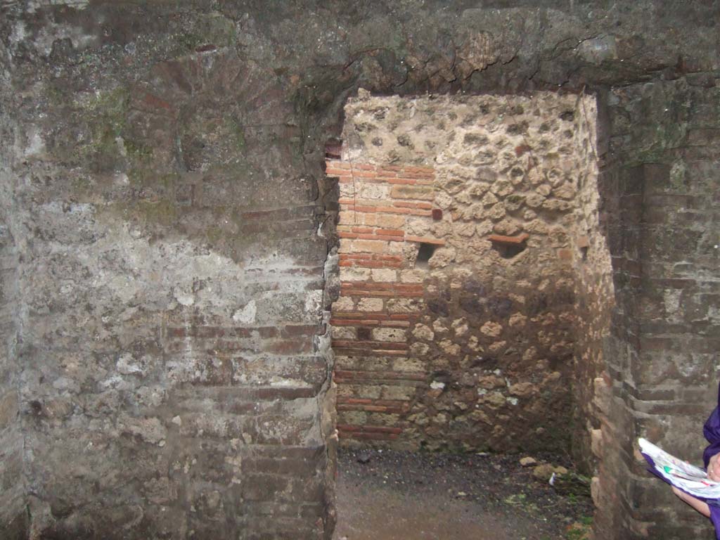 VII.14.9 Pompeii. December 2005. Room 10, south wall, with doorway to room 9, and filled-in niche, on left.