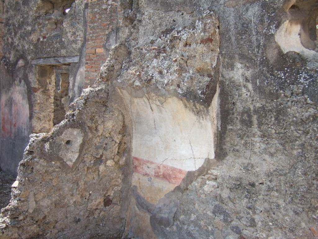 VII.15.9 Pompeii. September 2005. Looking west to south-west corner of triclinium at rear of atrium.  In the recess for the bed there are remains of plaster painted with a yellow zoccolo (plinth/dado) above which was a red band, the upper wall was painted white. On the right is a circular window next to the recess.

