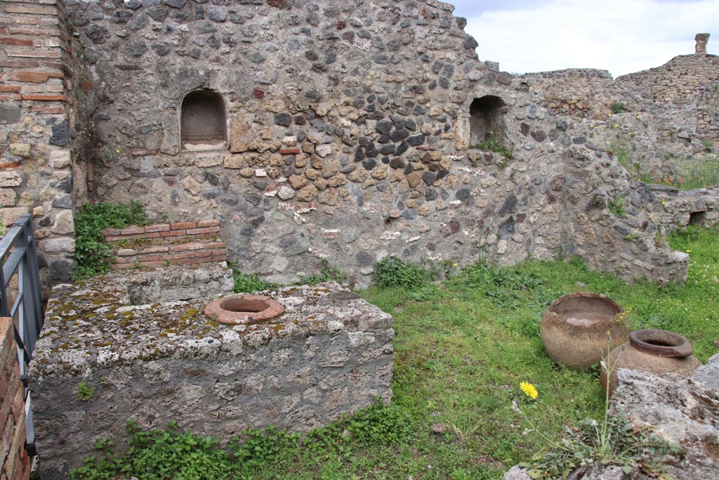 VII.16.7 Pompeii. May 2024. 
Looking west towards entrance doorway, on left, counter with display shelves and inset urn/s, and west wall with two niches.
Photo courtesy of Klaus Heese.
