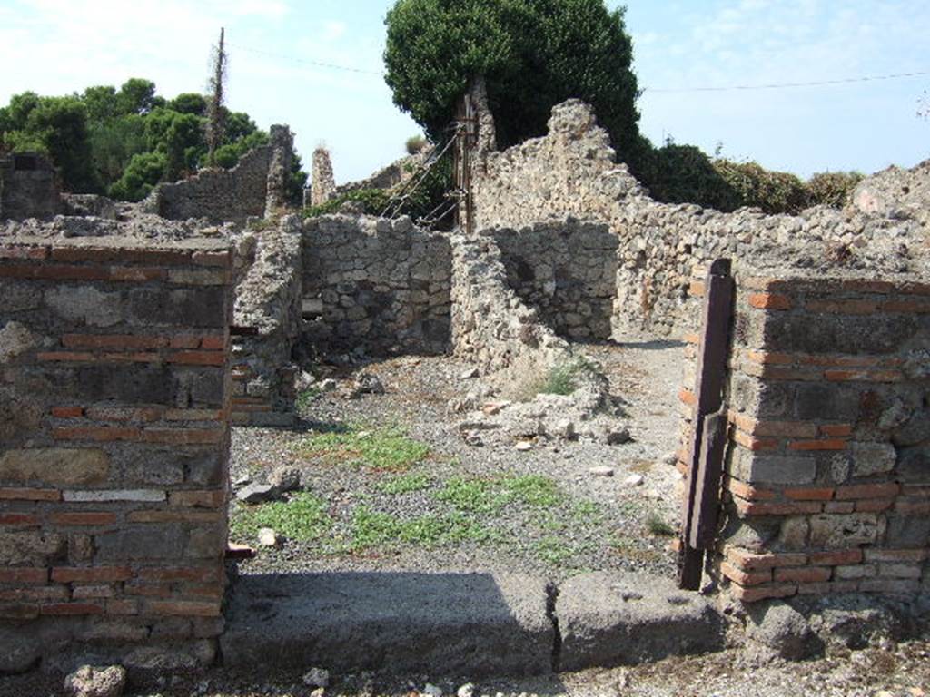 VII.16.9 Pompeii. September 2005. Looking west through entrance doorway.
According to Fiorelli 
In questo trovasi innanzi tutto un forno, separato da altre localita cui prima stava congiunto, e con due  celle adiacenti, una delle quali servita certamente di apotheca.
See Pappalardo, U., 2001. La Descrizione di Pompei per Giuseppe Fiorelli (1875). Napoli: Massa Editore. (p.161)
(translation: An oven was found in this, separated from other places with which it had been first joined, and with two adjacent rooms, one of which would have certainly been used as a storeroom/cupboard.)
