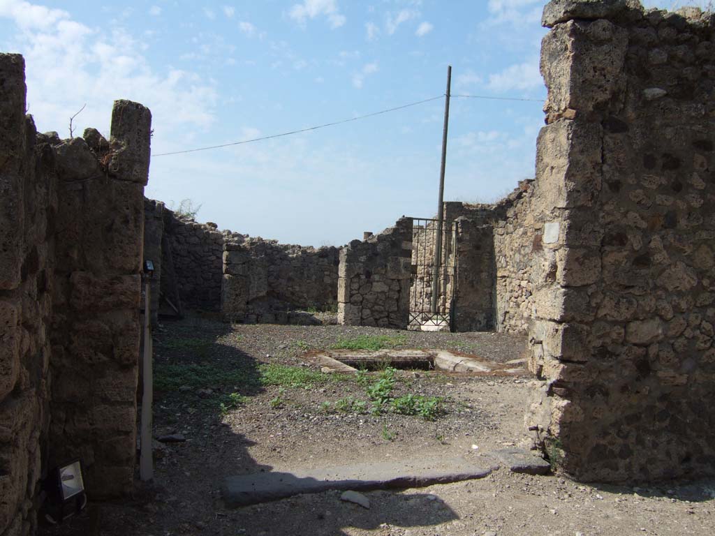 VII.16.12 Pompeii. September 2005. Entrance doorway, looking west.
According to Fiorelli –
“Piccola casetta posta in comunicazione con quella seguente, piu nobile ed antica, ed alla quale serviva forse di uscita secondaria l’ampia porta, che introduce in un atrio tuscanico, con impluvio e due bocche di cisterna di pietra vesuviana, sulla cui parete meridionale era graffito.
Di fronte stanno due cubicoli, ed accosto una fauce, che menando a stanze sottoposte, teneva a sinistra altre celle, e a destra comunicava con la casa attigua.”
See Pappalardo, U., 2001. La Descrizione di Pompei per Giuseppe Fiorelli (1875). Napoli: Massa Editore. (p.161).
(translation: "Small house placed in communication with the next following one, more noble and ancient, and to which perhaps the wide doorway was used as a secondary exit, which leads into a Tuscan atrium, with impluvium and two cistern-mouths of Vesuvian stone, on the south wall of which was a graffito (see page 161).
Facing were two cubicula, and nearby a corridor which leads to the underneath rooms, having other rooms to the left, and on the right communicating with the adjoining house.")