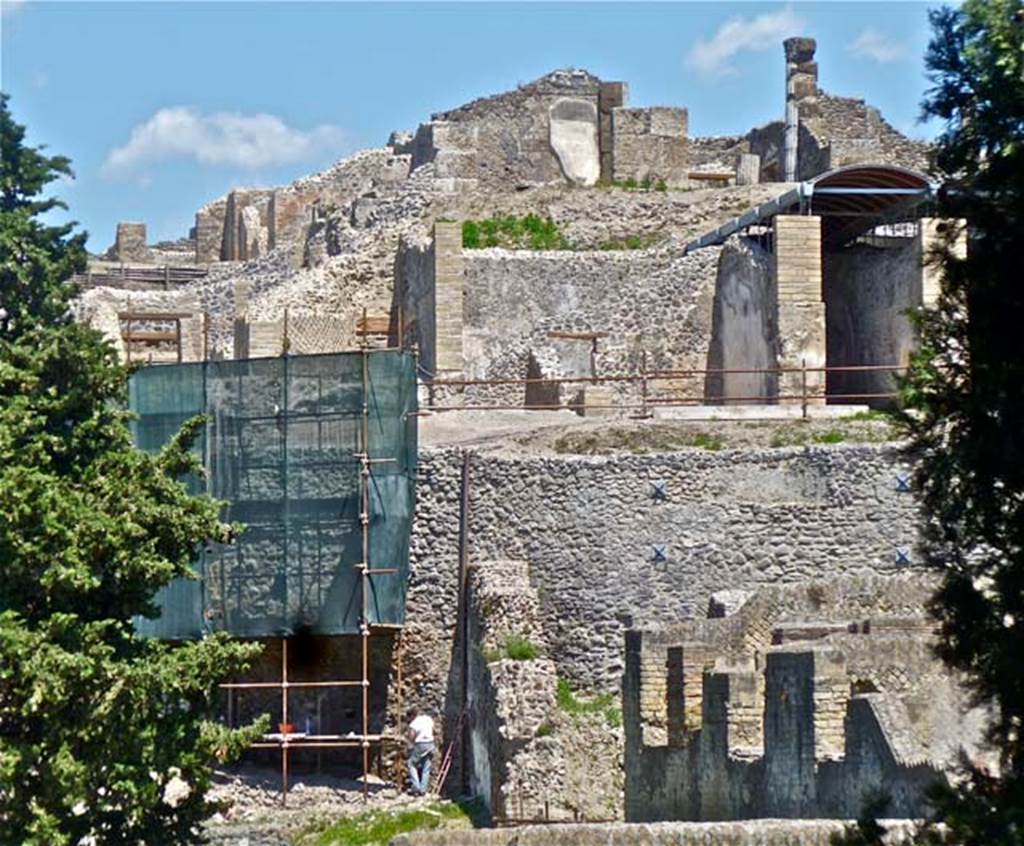 VII.16.16/15/13 Pompeii. May 2011. Looking east from rear. Part of VII.16.16/15 can be seen behind the scaffolding. The restored unroofed rooms 34, 33, and roofed room 32, which are on the lower level of VII.16.13, can be seen on the right of centre of the photo.
Photo courtesy of Michael Binns.
