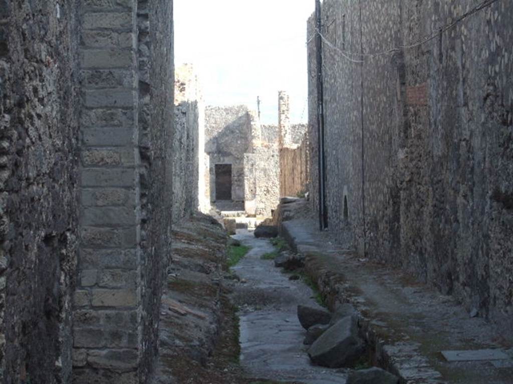 VII.6 Pompeii. September 2005. Vicolo del Farmacista, looking south.    VII.16 on right.  According to Garcia y Garcia, in 1943 the internal unexcavated area between VII.16. A and B (20 and 21) along the Vicolo del Farmacista was hit by a bomb. It fell on the soil not yet excavated and demolished the perimeter wall for a length of 4m x 3m and a part of the escarpment in two areas for 8 metres..
See Garcia y Garcia, L., 2006. Danni di guerra a Pompei. Rome: LErma di Bretschneider. (p.137)

