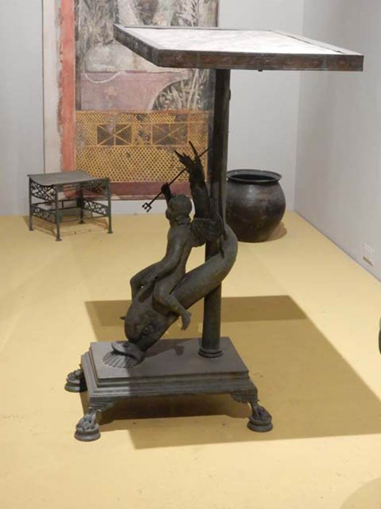 VII.16.17-22, Pompeii. May 2018.
Bronze stool decorated with palms and lotus flowers. Archaeological Park of Pompeii, inv. 13355.
and Pot (olla) in bronze for the boiling of foods, Archaeological Park of Pompeii, inv. 14069.
And Table in bronze and marble decorated with a cupid riding a dolphin, Archaeological Park of Pompeii, inv. 13371 .
Photo courtesy of Buzz Ferebee.