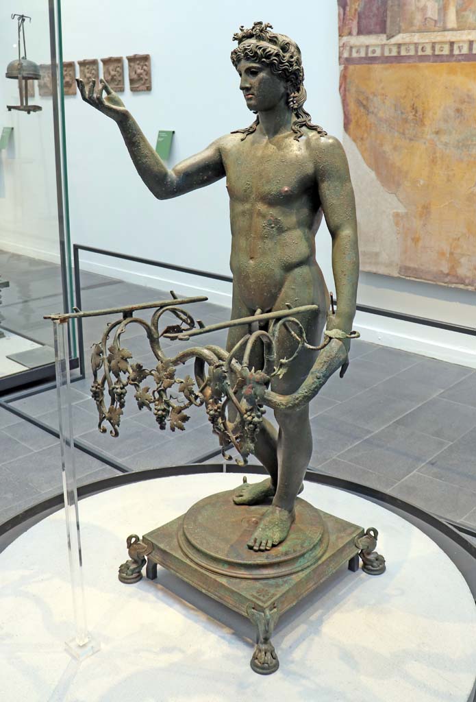 VIII.1.4 Pompeii. February 2021.
Detail of bronze Ephebus as an oil lamp holder, found in dining room of VII.16.17/22.
The terracotta plaques, on the wall to the left, may have been found during the excavation of the foundations of the Greek temple.
(See p.103, of Fiorelli, G., 1897. Guida di Pompei, Museo Pompeiano terracotta items, below, for more photos).
Photo courtesy of Fabien Bièvre-Perrin (CC BY-NC-SA).
Parco Archeologico Pompei, inventory number 13112.