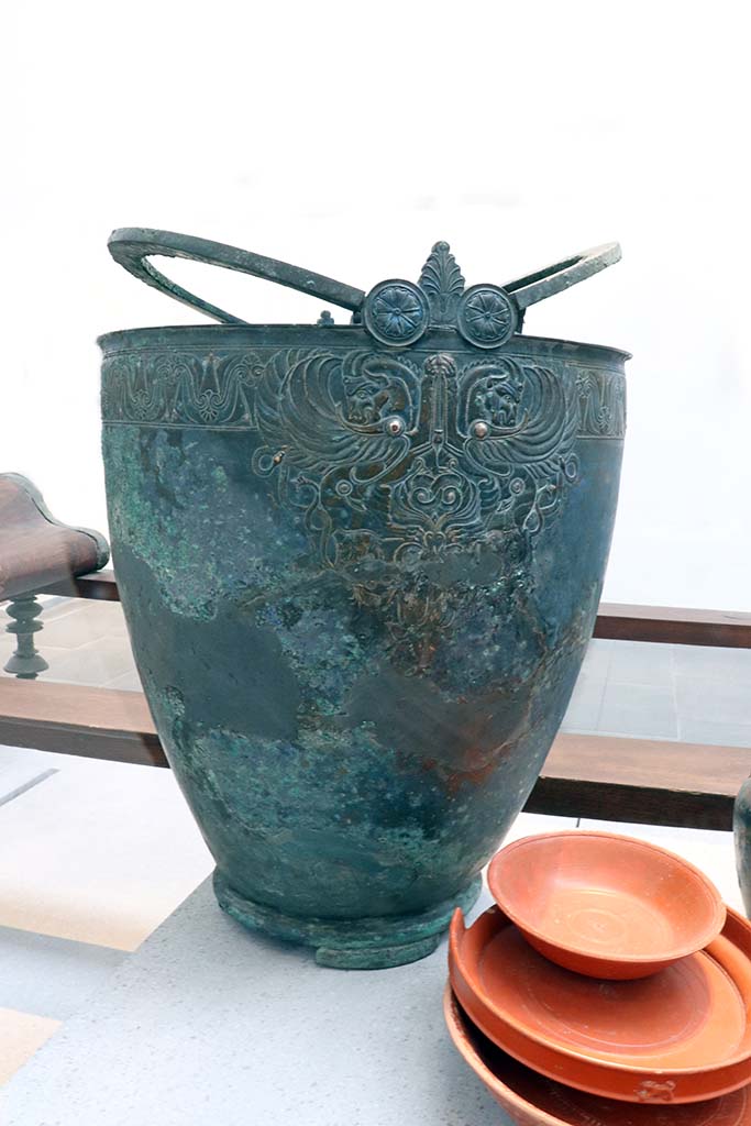 VIII.1.4 Pompeii. February 2021.
Bronze pitcher with handles decorated with human faces, from House of Menander at I.10.4.
Photo courtesy of Fabien Bièvre-Perrin (CC BY-NC-SA).