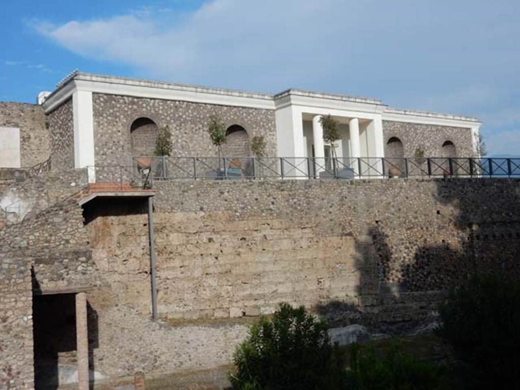 VIII.1.a Pompeii. May 2015. Looking east to north end of portico, remains of the city walls, and modern Antiquarium, above. Photo courtesy of Buzz Ferebee.