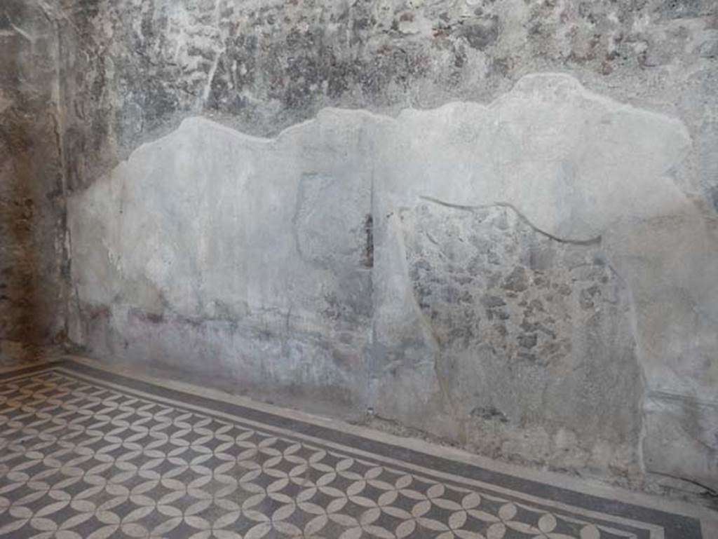 VIII.2.1 Pompeii. May 2018. Looking towards east wall of triclinium. Photo courtesy of Buzz Ferebee.
This wall originally would have been painted with a red zoccolo/dado which was painted in square panels with birds and plants, separated by compartments which were placed under those above which contained candelabra in the middle zone of the wall but now lacking all colour, these separated the yellow panels with spaces that were decorated.
According to Pagano and Prisciandaro -
“On the long side of the atrium itself, where there was the ala, there were also two rooms, one that had a mosaic floor - black with white circles woven onto a black-background, and red zoccolo/dado, the walls mostly painted with grotesques, and in the spaces that these left between them, alternatively placed were some animated, and some views; in one of which there is the fall of Icarus, and in the other Ulysses tied to the ship's mast, to escape the flattery of the Sirens. The upper part of the plaster of this room was adorned with various paintings on a white background; there was also a few portions of the stucco cornice.” 
See Pagano, M. and Prisciandaro, R., 2006. Studio sulle provenienze degli oggetti rinvenuti negli scavi borbonici del regno di Napoli. Naples: Nicola Longobardi, 
(p.93)
References: 16th May 1800, PAH 1,2,74, La Vega, 159.
