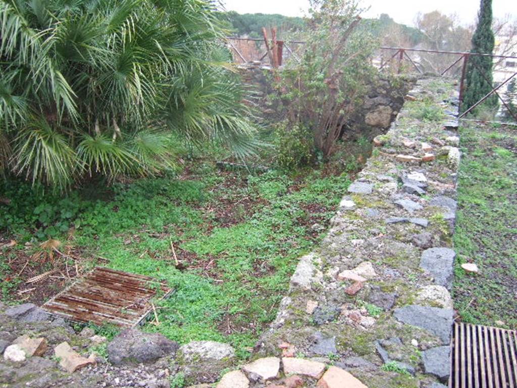 VIII.2.1 Pompeii. December 2005. Looking south along west side of peristyle garden. According to Jashemski, the peristyle garden at the rear of the tablinum was excavated in 1799. It was enclosed on four sides by a portico supported by twelve brick columns. It was called a hanging garden by Mazois and Fiorelli, because it was built on the volcanic ledge. To give light to the rooms below,openings were cut in the floor which supported the columns. Around the edges of the garden was a gutter. There was a fine view over the Bay and the mountains from the terraces on two levels at the rear of the house.
See Jashemski, W. F., 1993. The Gardens of Pompeii, Volume II: Appendices. New York: Caratzas. (p.205)
