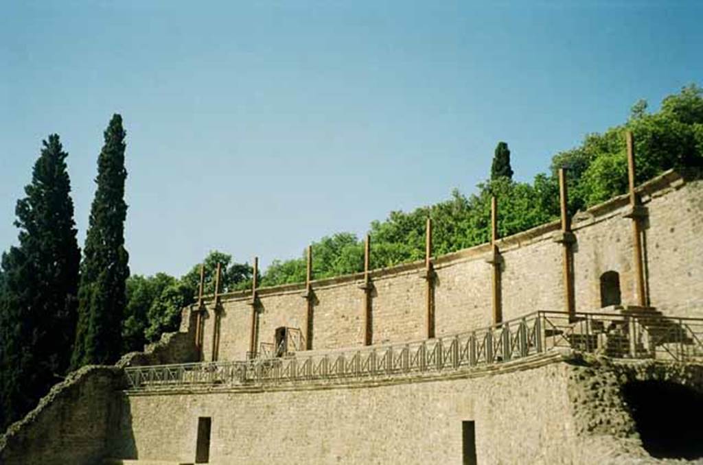 VIII.7.20 Pompeii. June 2010. The lower area is the remains of the summa cavea supported by a vaulted corridor. The tall wall at the rear had projecting basalt blocks. These were to support strong wooden masts that held the awning or velum that protected the spectators from the sun. Photo courtesy of Rick Bauer.