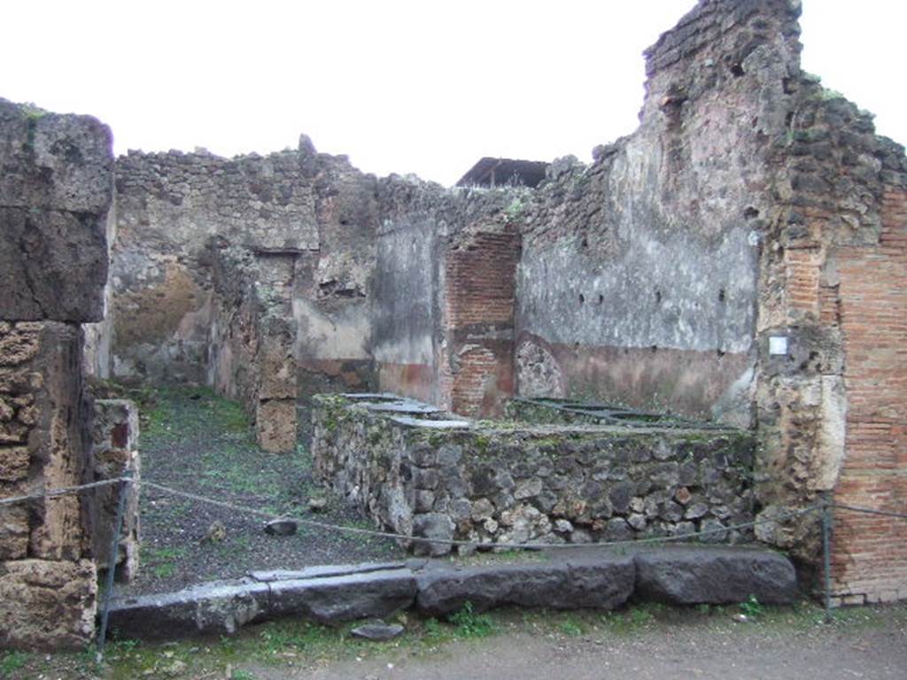 IX.1.8 Pompeii. December 2005. Looking east from Via Stabiana. The room at the front had a bench embedded with five large terracotta containers for provisions, support-holes for shelving for utensils, and a hearth on the north side near the doorway. At the rear, (towards the east side), was a room possibly used as a dining room for the customers, as well as a narrow room where the stairs to the upper floor were found, underneath the stairs was the latrine.