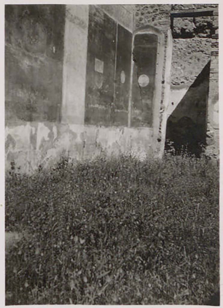 IX.1.22 Pompeii. Pre-1943. Room 1, west wall and north-west corner of atrium. Photo by Tatiana Warscher.
According to Warscher –
“On the west wall, four red panels remained; divided by vertical narrow strips; nearly in the middle there was a wider strip, of around 0.60.
In the centre of the panels rectangles and medallions remained. On the rectangles, attributes of the deities were seen, with landscapes on the medallions.  The medallions would have been on the north wall, and at least one remained on part of the wall near to the doorway of the room in the north-west corner of the atrium.  Fortunately, the German Institute (DAIR) conserved two copies of watercolours of the landscapes.”
See Warscher, T. Codex Topographicus Pompeianus, IX.1. (1943), Swedish Institute, Rome. (no.111a), p. 195.
