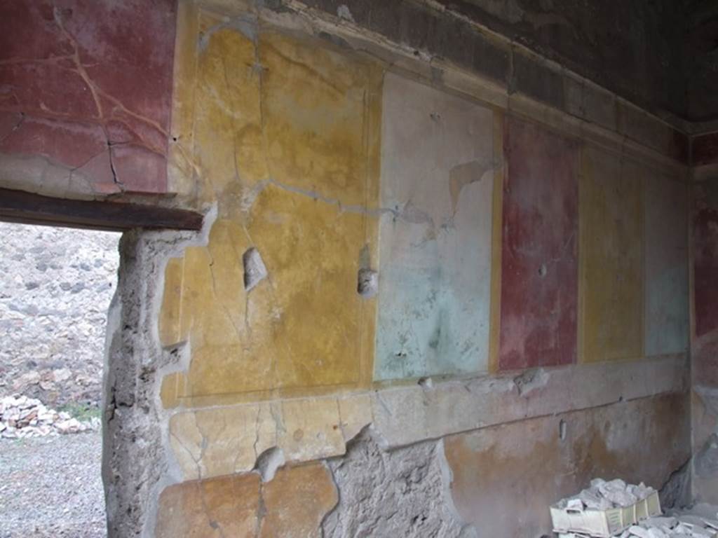 IX.1.22 Pompeii. December 2007. Room 25, west wall of room in north-east corner of peristyle. Starting from the left the figures seen in the small rectangular panels would have been –
a) A man, walking half to the left and half towards the viewer. He was naked, but held a robe with both hands which fell from behind the lower part of his body, and was visible between his legs. Each of his hands held a border. 
b) Two wrestlers who could be named Hercules and Antaeus. The one on the right had embraced the opponent from behind and held him up high resting him on the thigh – but  it was not possible to distinguish whether it was on the right or left. This one painfully took with the left hand the left arm of his conqueror. 
c) A naked man, who put the stretched left leg towards the right, whilst the right leg was curved behind. The right arm was stretched from the shoulder towards the right, and it seemed as if his hand was disproportionately large, as if armed with a boxing-glove. Probably here one recognised a boxer.
d) Very faded. I seem to recognise a standing figure turned to the left, which could have been a boxer, corresponding to figure c).
e) A female figures in long robe. It seemed that the head was seen faced forward but that the rest of her moved towards the right; with her right hand extended from which hung an object, not recognisable. The left hand held a long stick, either a spear or a sceptre, from the top of which, a line nearly horizontal stretched above her head.
f) A man, walking quickly half to the right, half towards the viewer, with the curved right leg put forward. Holding a shepherd’s crook in his right hand, with the curved part up, whilst near to the right shoulder as if leaning on it, was a high and narrow object, but not definable.
See Mau in BdI, 1876, (p.101-2)
