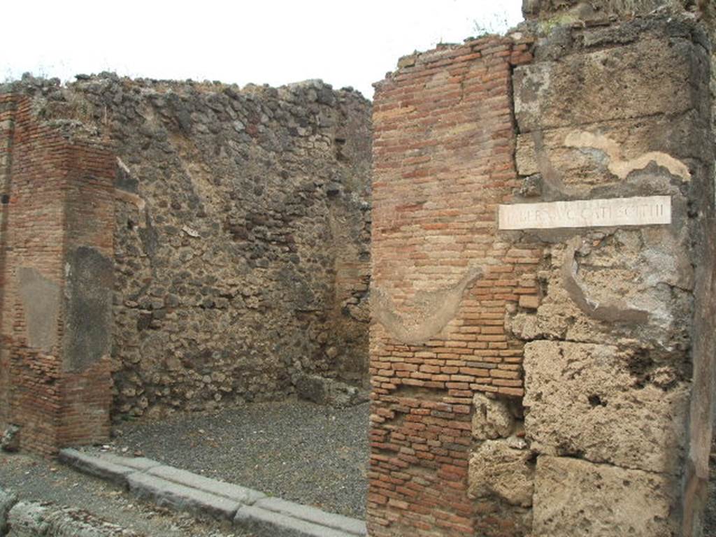 IX.3.13 Pompeii. May 2005. Entrance, looking towards west wall, and site of stairs to upper floor. The white plaque is the name plaque for IX.3.14.  

